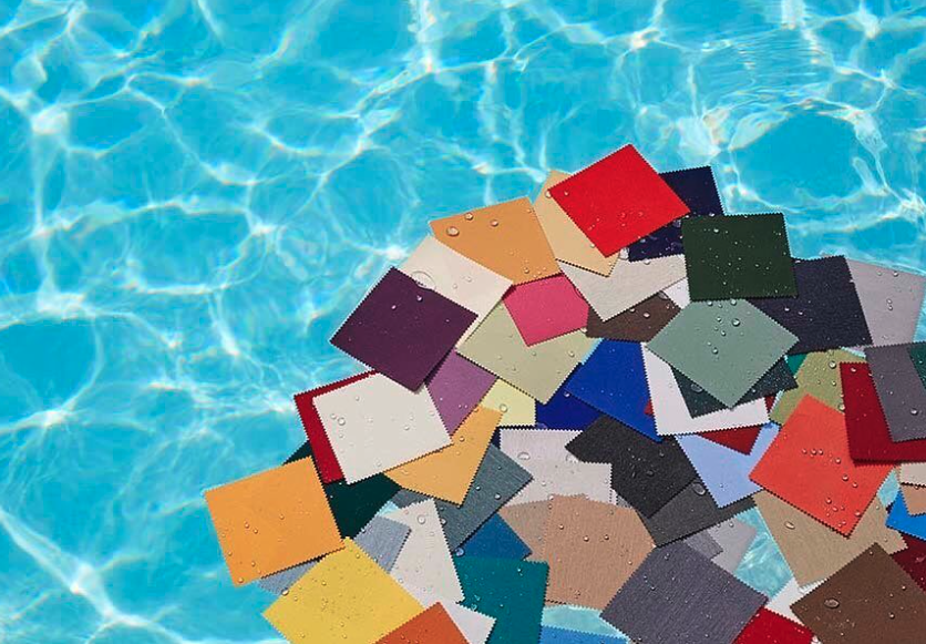 Colourful Dickson awning fabric swatches floating on rippling pool water