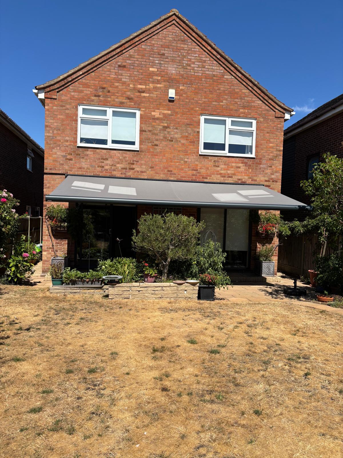 Anthracite Aura Plus awning extended across two sets of sliding doors at a Hornchurch home