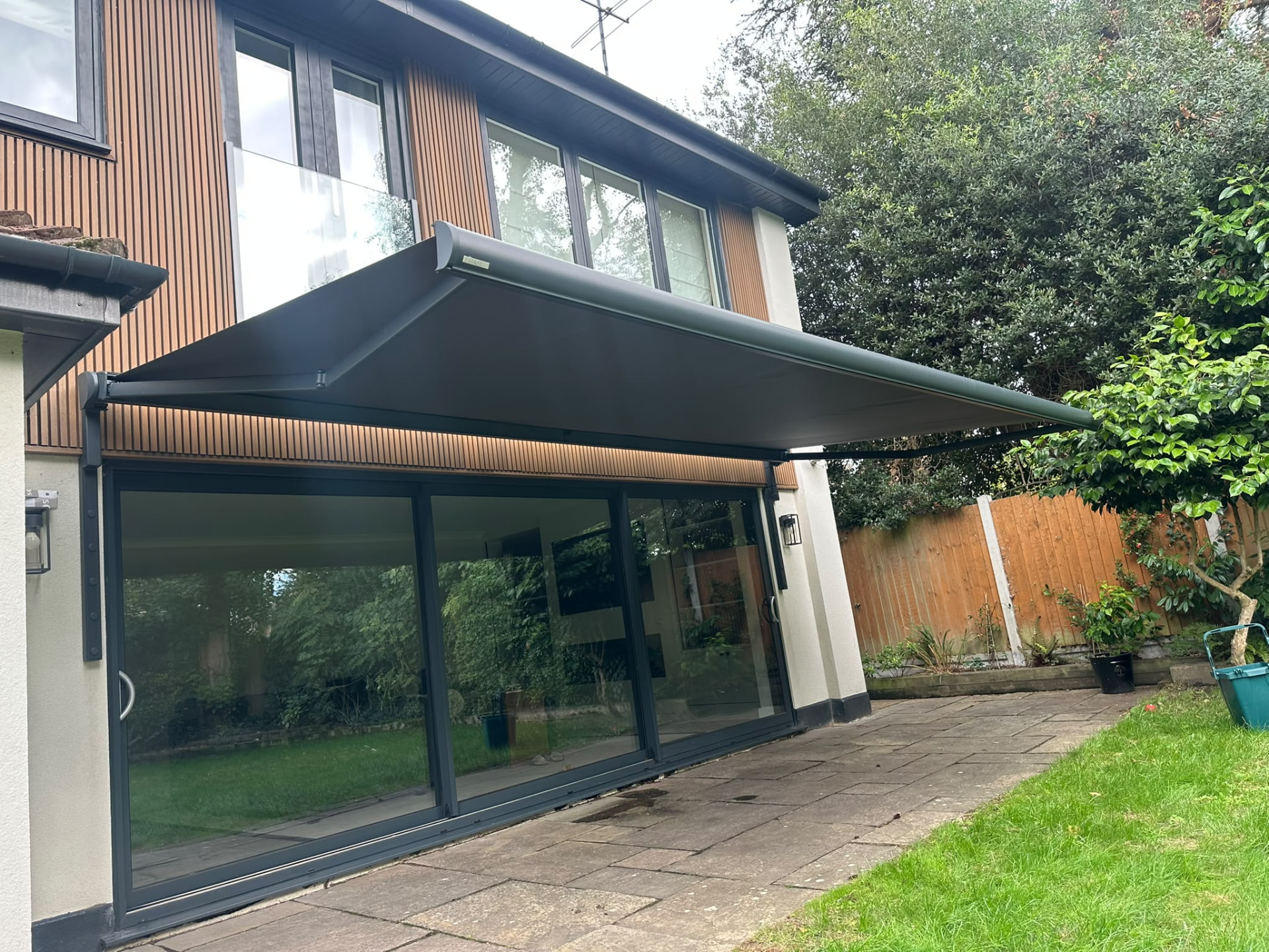Anthracite Aura Plus awning extended over a modern patio in Brentwood