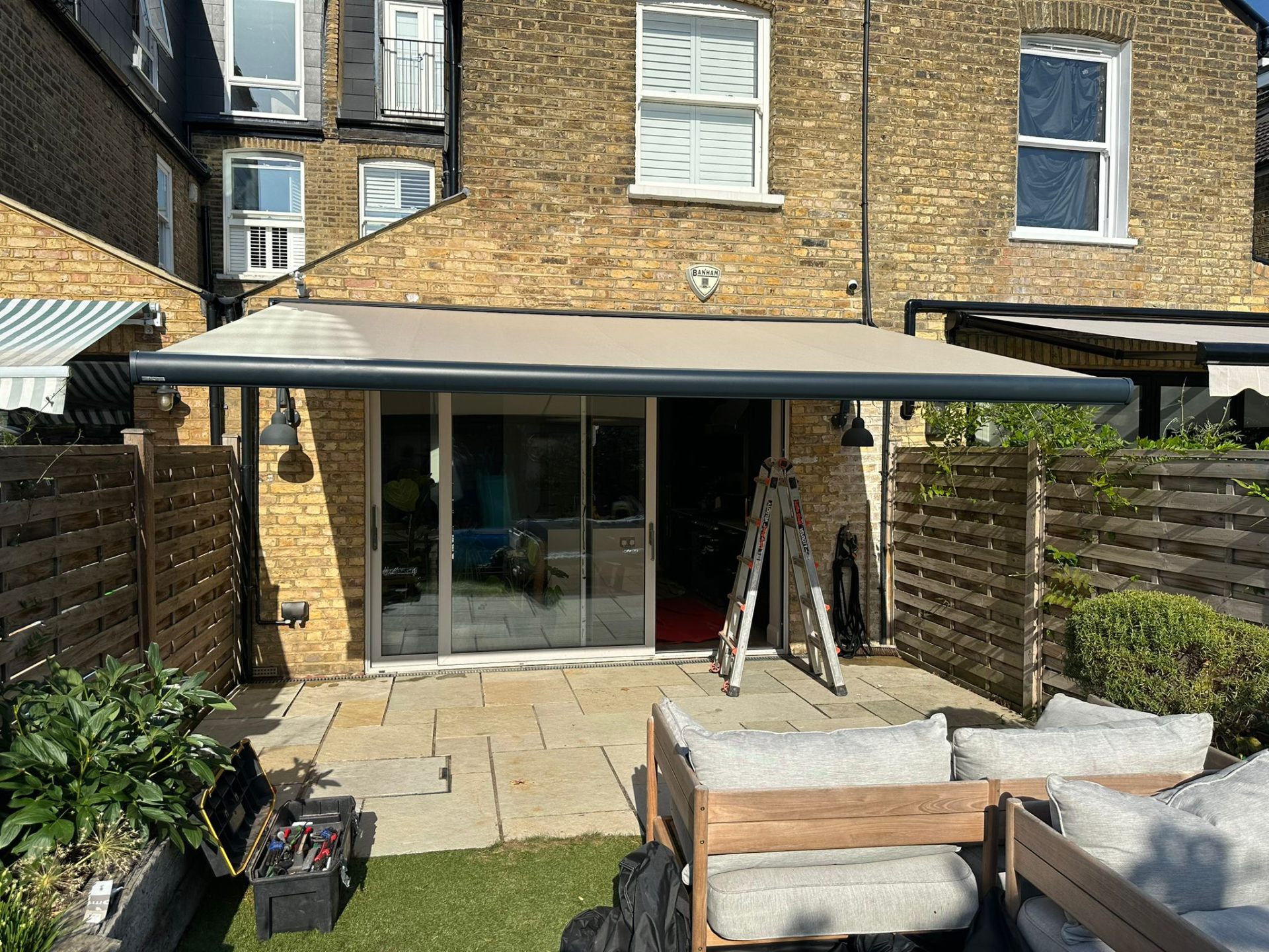 Anthracite Aura Plus awning fully extended over patio at Barnes terraced home