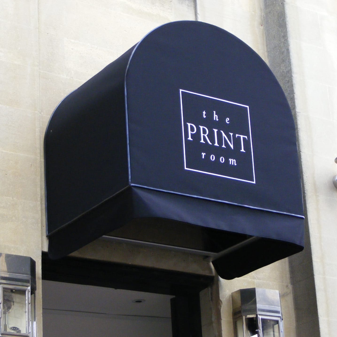 Deep burgundy scalloped commercial canopy over a London boutique storefront