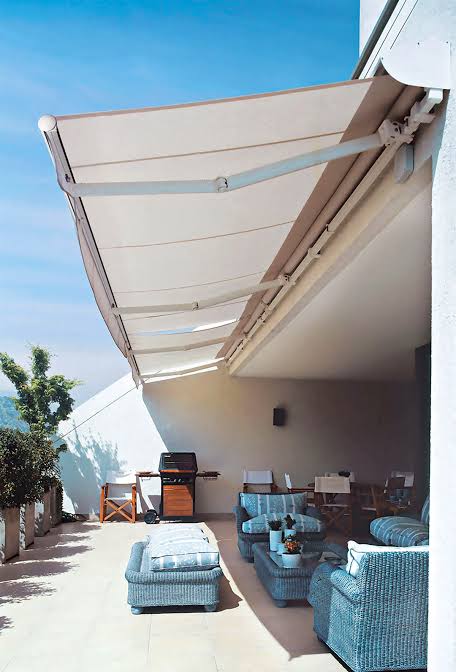 Cream retractable awning over a rooftop terrace with lounge seating