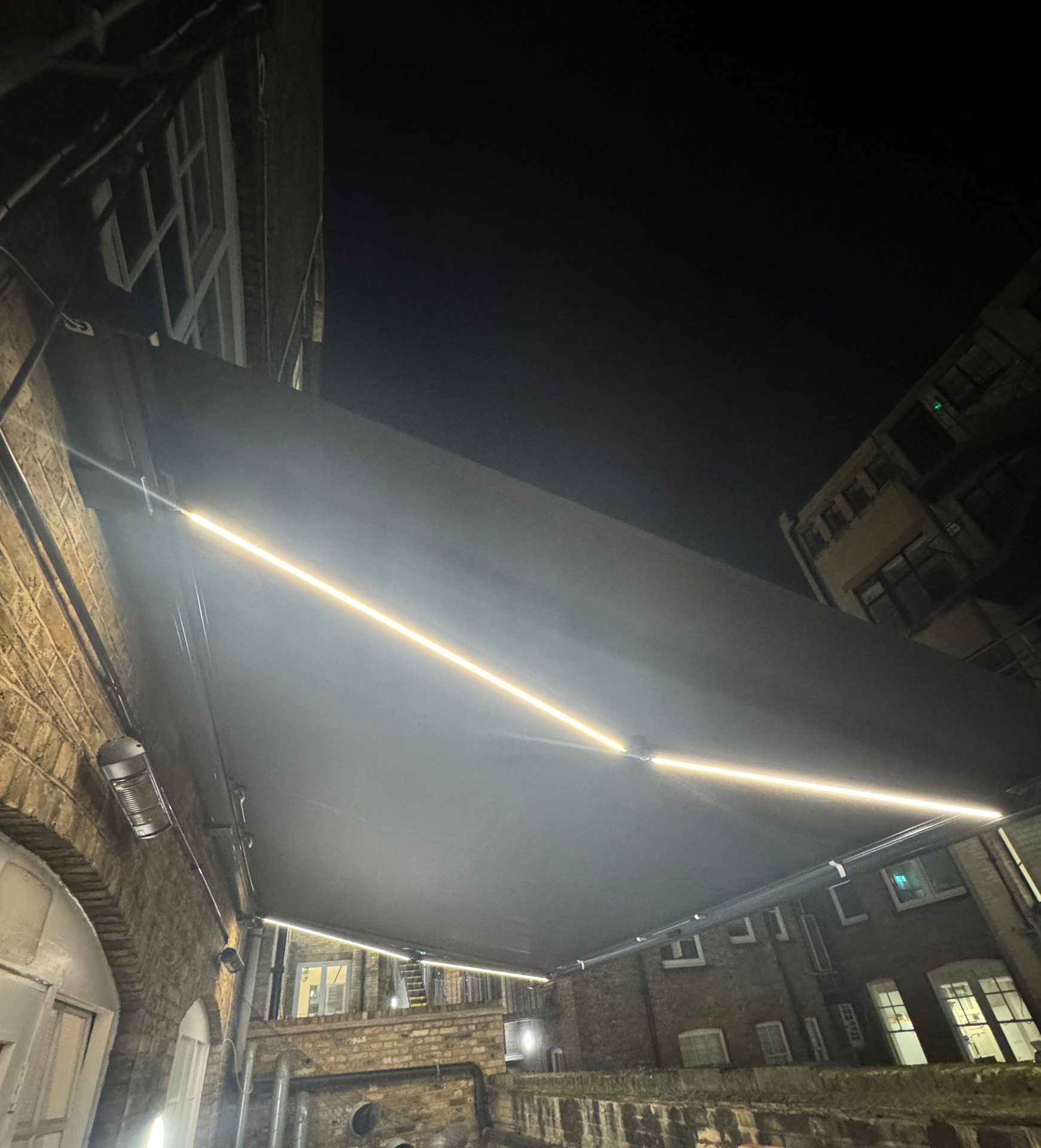 Awning with integrated LED strip lighting along the arms glowing warmly at night